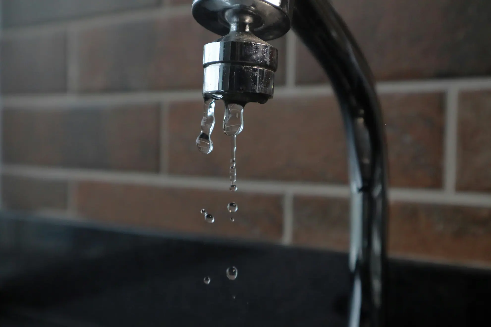 Close-up of a kitchen faucet pouring clear, filtered drinking water